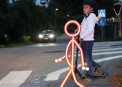 Barn med sparkcykel väntar på att gå över vägen